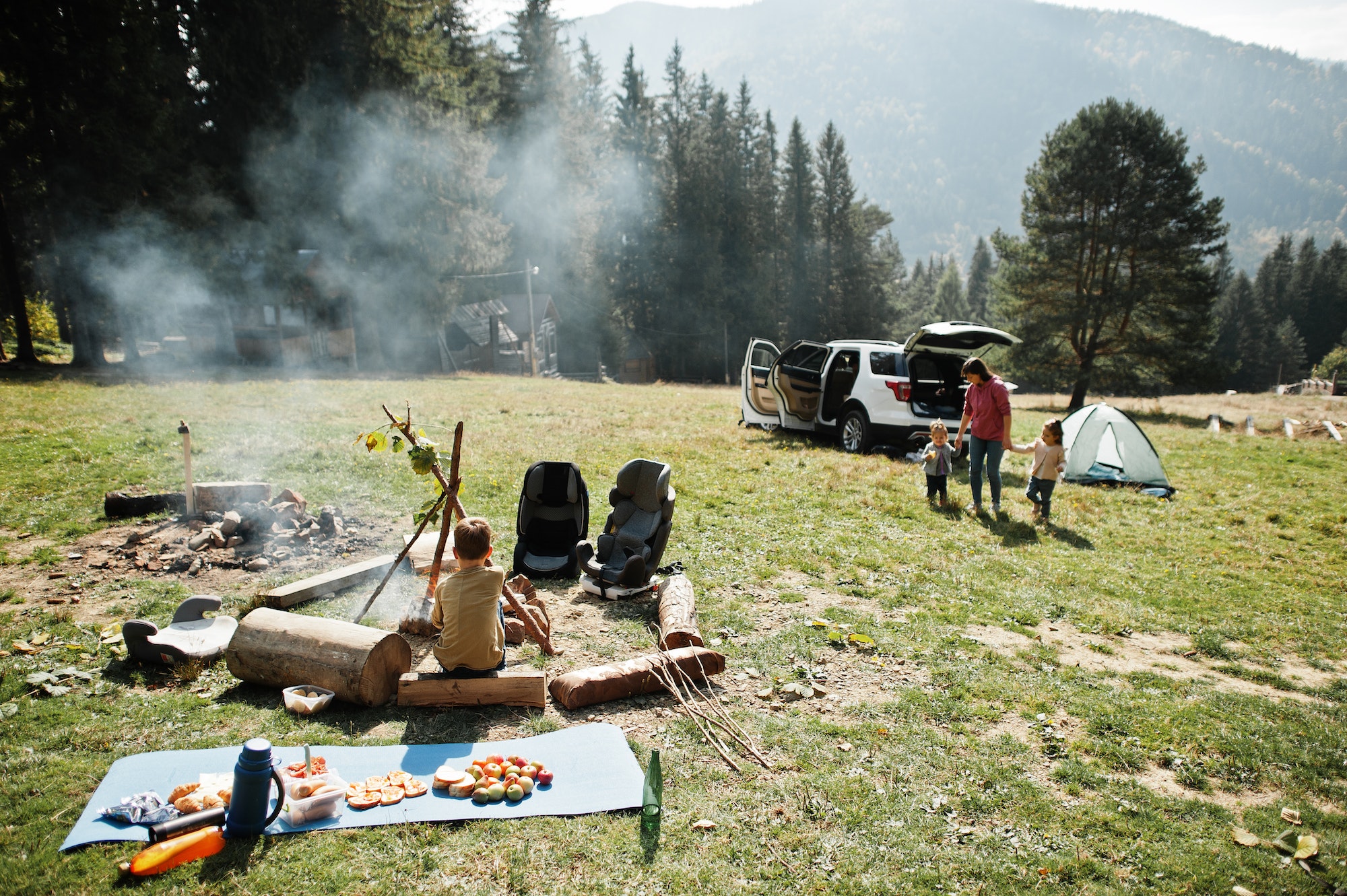 Family bonfire in mountain. Autumn hike and camp weather. Warming and cooking near flame together.