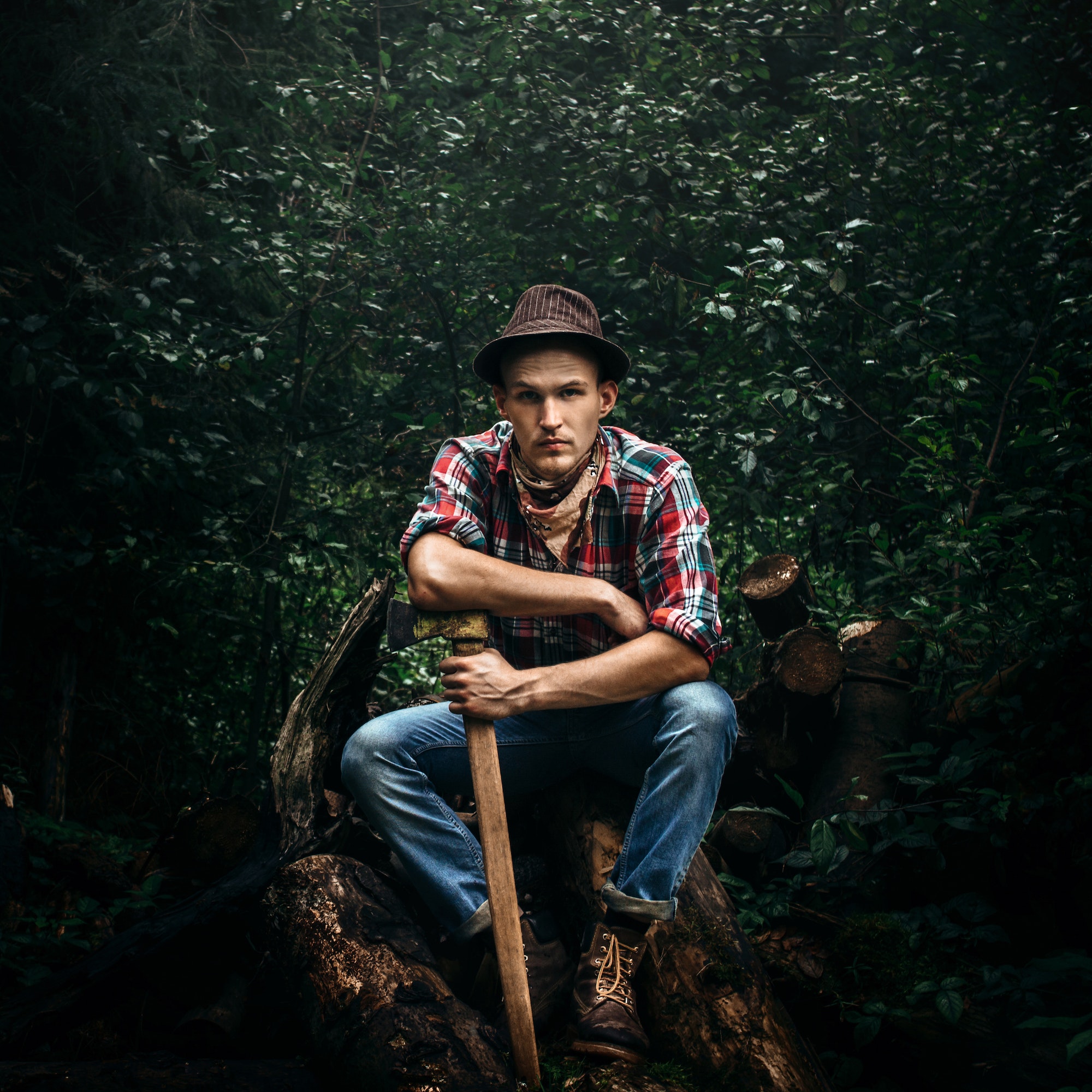 stylish hipster lumberjack with ax in the sunny forest in mountains